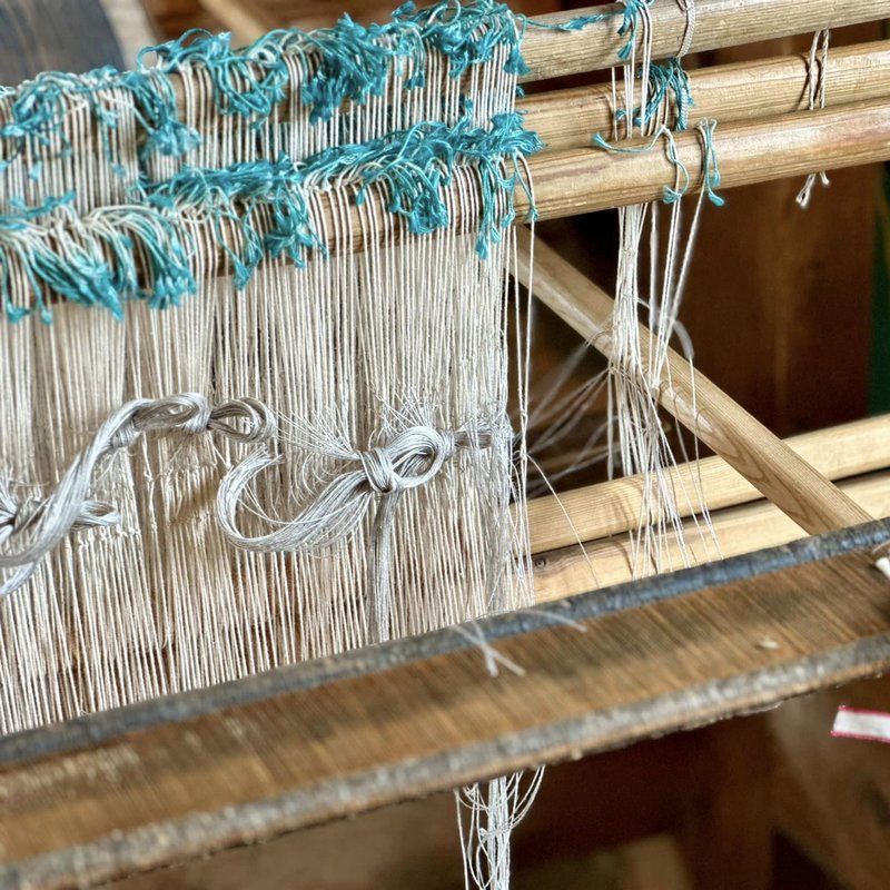 An upright loom with fine linen being woven